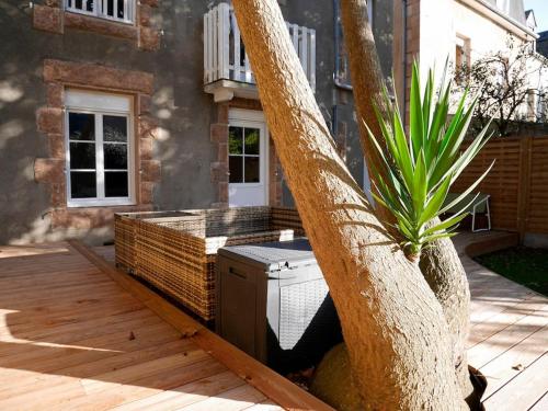 a tree sitting on a deck next to a house at CLINT HOUSE - Appartement "Jardin de granit rose" in Perros-Guirec