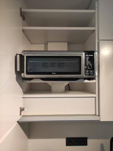 eine Mikrowelle auf einem Regal im Kühlschrank in der Unterkunft Black & White Apartment in Saarbrücken