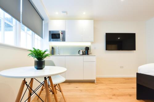 a kitchen with white cabinets and a white table at StayPrime Marylebone Serviced Apartments in London