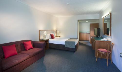 
a hotel room with a bed, chair, desk and a television at Bayswater Tweed in Tweed Heads
