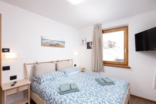 a bedroom with a bed and a tv and a window at Pianeta Oro Chalet Allegra in Livigno