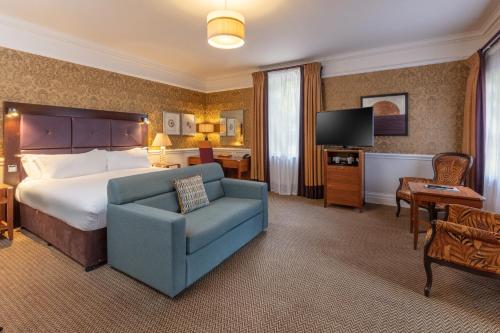 a hotel room with a bed and a blue chair at The Manor House at Norton Park in Winchester