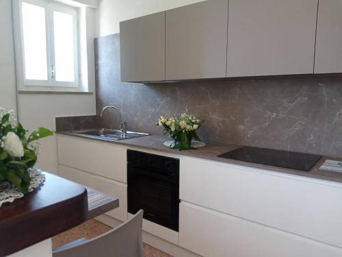 una cocina con armarios blancos y un fregadero con flores en la encimera en Appartamento L'Airone Cenerino, en Canzo