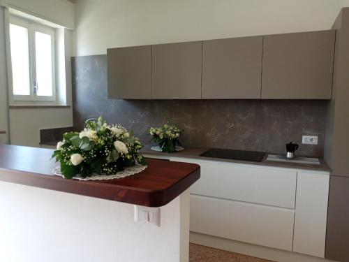 a kitchen with white cabinets and a counter with flowers on it at Appartamento L'Airone Cenerino in Canzo