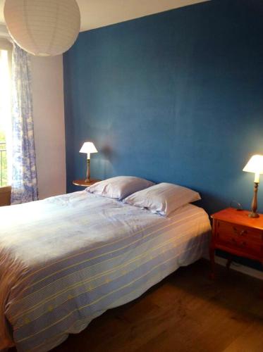 une chambre avec un lit avec un mur bleu dans l'établissement Appartement confortable à Saint-Martin, 60 m², jardin spacieux, à Saint-Martin-sous-Vigouroux