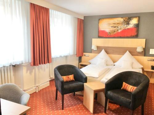 ein Hotelzimmer mit einem Bett und zwei Stühlen in der Unterkunft Hotel Garni "Brauerei Keller" in Miltenberg