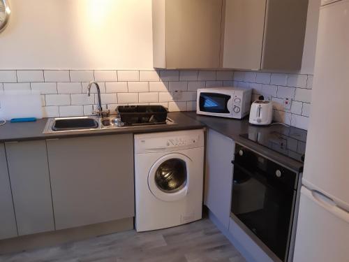 a kitchen with a washing machine and a microwave at Carvetii - Iona House, 2nd floor apartment sleeps up to 6 in Kirkcaldy