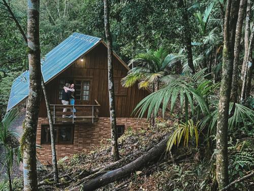 ein Paar steht auf dem Balkon einer Hütte im Wald in der Unterkunft Chalé da Pedrinha in Volta Grande