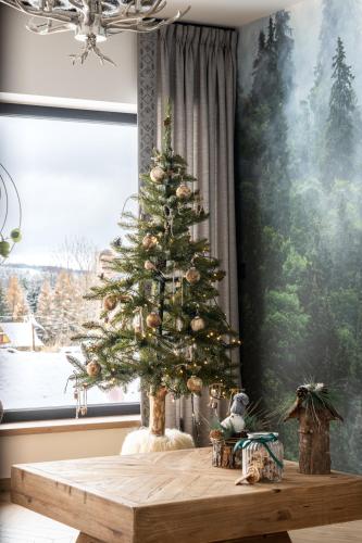een kerstboom op een houten tafel voor een raam bij VILLA TEDDY BEAR Zakopane in Zakopane