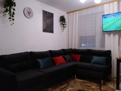 a living room with a black couch and a tv at Mieszkanie w Centrum Chełma in Chełm