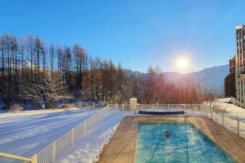 une piscine couverte de neige avec le soleil en arrière-plan dans l'établissement *Nouveau* Pied des pistes * Piscine ext. chauffée*, à L'Alpe-d'Huez