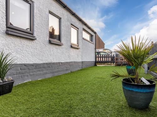 a yard with grass and plants next to a building at Beinn Mhor View in Lochboisdale