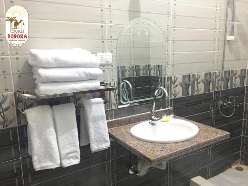 een badkamer met een wastafel, een spiegel en handdoeken bij DoroKa Nubian House in Shellal