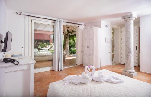 due cigni bianchi seduti su un letto in una stanza di Villas Resort Wellness & SPA a Castiadas
