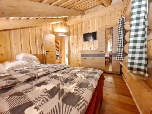 1 dormitorio con 1 cama en una habitación con paredes de madera en Falkenblick en Hochrindl