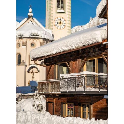 a building covered in snow with a clock tower at Loft im Stadl in Innervillgraten
