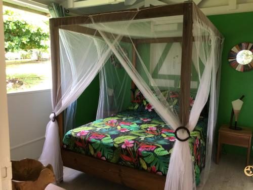 a bed with a canopy in a room with a window at Grand bungalow avec piscine et vue mer in Bouillante