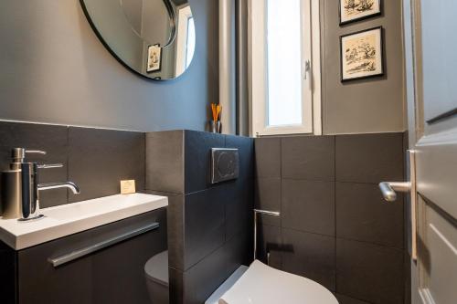 une salle de bain avec toilettes, lavabo et miroir dans l'établissement Veeve - Pompidou Hideaway, à Paris