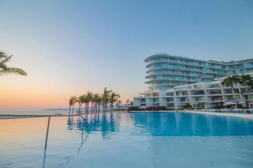 una piscina con palmeras y un edificio en Suites @ Aria Ocean, en Nuevo Vallarta 