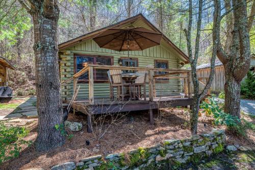 una cabaña en el bosque con una mesa y una sombrilla en stayNantahala - Smoky Mountain Cabins and Luxury Yurts, en Topton