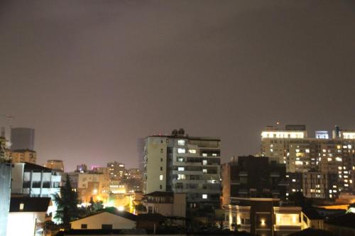 uno skyline della città di notte con edifici illuminati di Cozy big apartment with balcony a Tirana