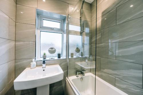 a bathroom with a sink and a glass shower at Wolviston House By Horizon Stays in Stockton-on-Tees