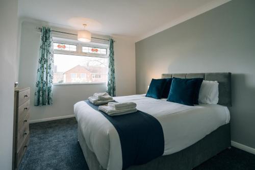 a bedroom with a large bed with blue pillows and a window at Dinsdale House By Horizon Stays in Stockton-on-Tees