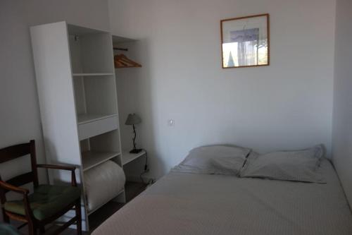 - une chambre avec un lit, une chaise et une étagère dans l'établissement Nice colline charmant studio indépendant au rdc d'une maison, à Nice
