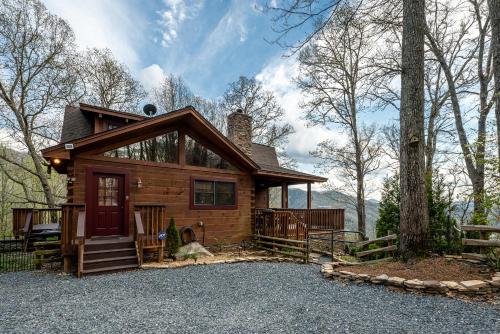 Cabaña de madera con puerta roja en el bosque en stayNantahala - Smoky Mountain Cabins and Luxury Yurts, en Topton