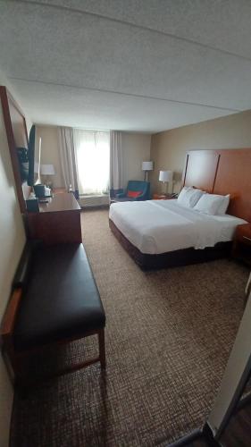 a hotel room with a large bed and a chair at Wingate by Wyndham Pittsburgh New Stanton in New Stanton