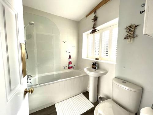 a bathroom with a tub and a toilet and a sink at Church View a first floor apartment in the heart of historic Topsham in Topsham