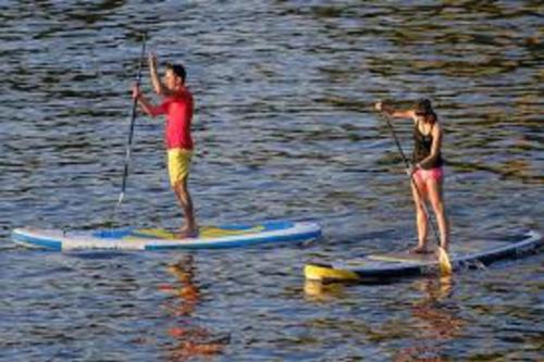 dos personas están de pie en tablas de paddle en el agua en Au Calme Absolu chez Nicolas en Lindry