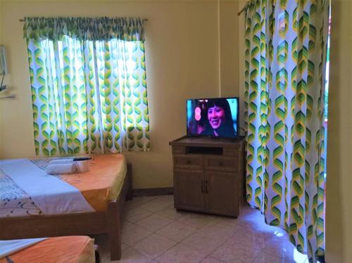 a room with a tv on a dresser with a bed at Ocean Breeze Inn in Boracay