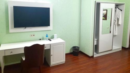 Habitación con escritorio, TV y silla. en Reikartz Sunkar Atyrau, en Atyraū