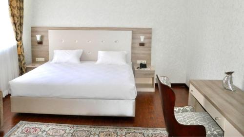 a bedroom with a white bed and a chair at Reikartz Sunkar Atyrau in Atyraū