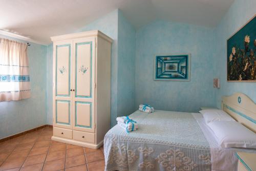 a blue bedroom with a bed and a cabinet at Affittacamere S'Alzola in Porto Rotondo