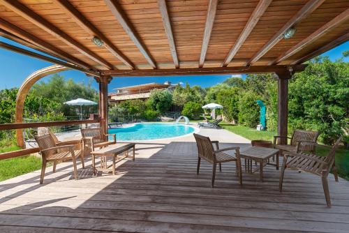 a wooden deck with tables and chairs next to a swimming pool at Affittacamere S'Alzola in Porto Rotondo