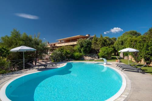 a swimming pool with chairs and umbrellas next to a building at Affittacamere S'Alzola in Porto Rotondo