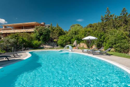 a swimming pool in a yard with chairs and an umbrella at Affittacamere S'Alzola in Porto Rotondo
