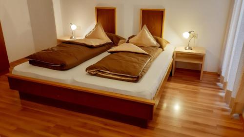 two beds in a room with two lamps on two tables at Apparthotel Maier in Soprabolzano