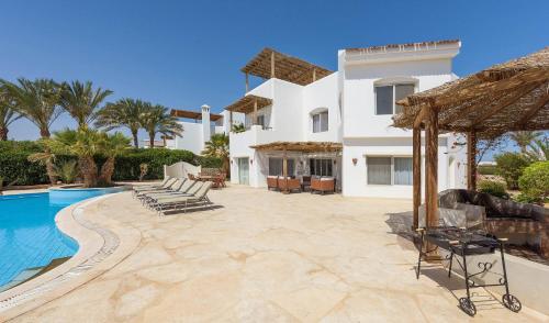 een villa met een zwembad en een huis bij Beautiful 4 bedroom White Villa with Heated Pool in Hurghada
