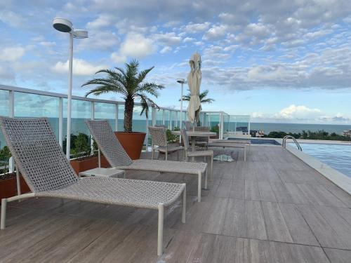 una terraza con sillas y una piscina en un edificio en Flat Atlântico Norte - Joao Pessoa a 200m del mar, en João Pessoa