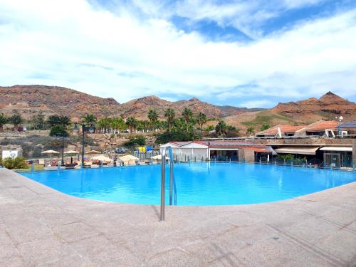 una gran piscina azul con montañas en el fondo en Villa Happiness - Luxury chalet with sea view, en Las Palmas de Gran Canaria