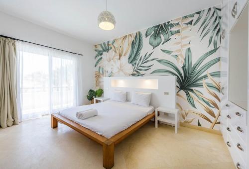 een slaapkamer met een bed met tropisch behang bij Beautiful 4 bedroom White Villa with Heated Pool in Hurghada