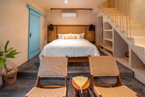 a bedroom with a bed and two chairs at Bacalari Hotel Boutique in Bacalar