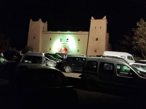 a parking lot with cars parked in front of a building at kasbah Dar Bahnini in Skoura