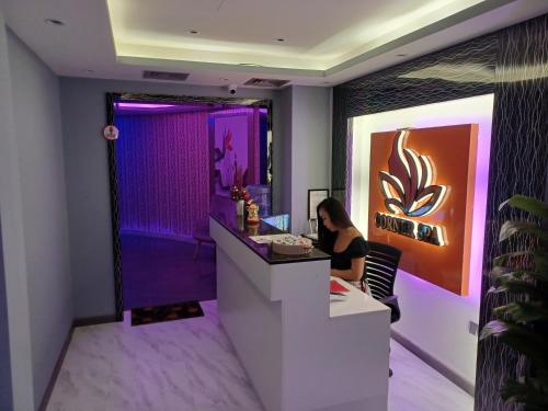 a woman sitting at a counter in a room with purple lighting at Al Qurum Resort in Muscat