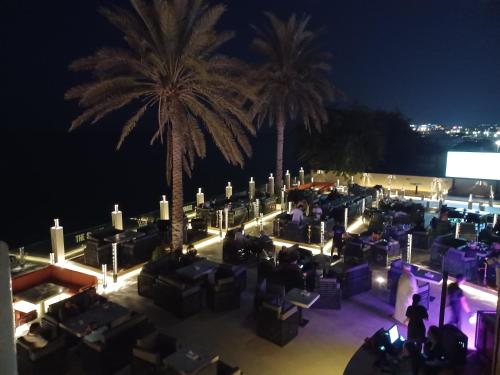 a group of people sitting in chairs under palm trees at night at Al Qurum Resort in Muscat