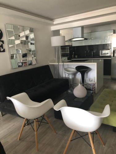 a living room with a black couch and white chairs at Habitacion Cama Queen in Bogotá