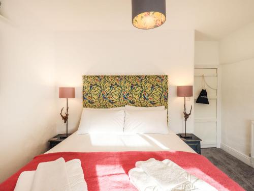 um quarto com uma grande cama branca e um cobertor vermelho em Violet Cottage em Ambleside